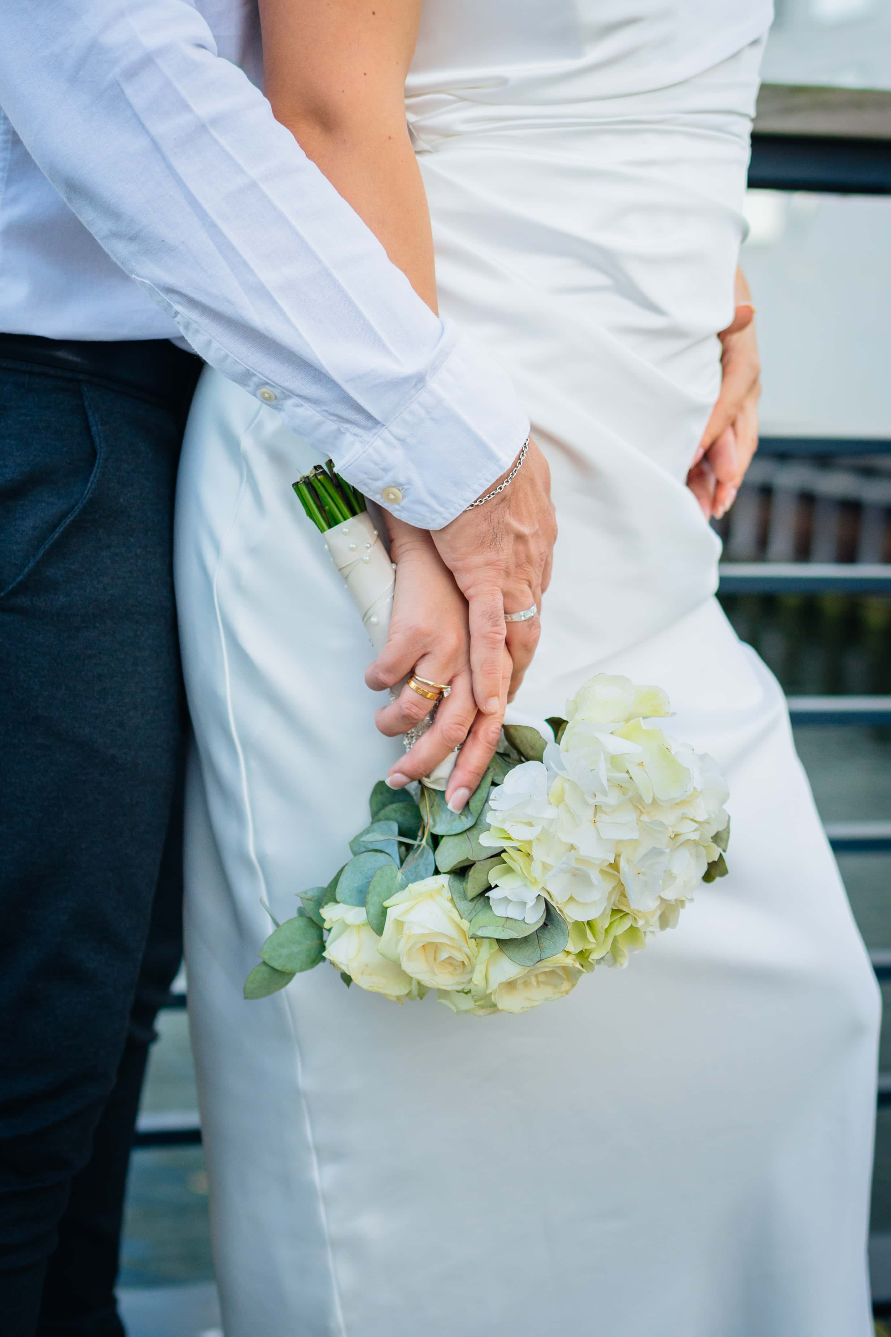 Mains des mariés sur un bouquet de roses et hortensias blancs, Félix Orain photographe mariage