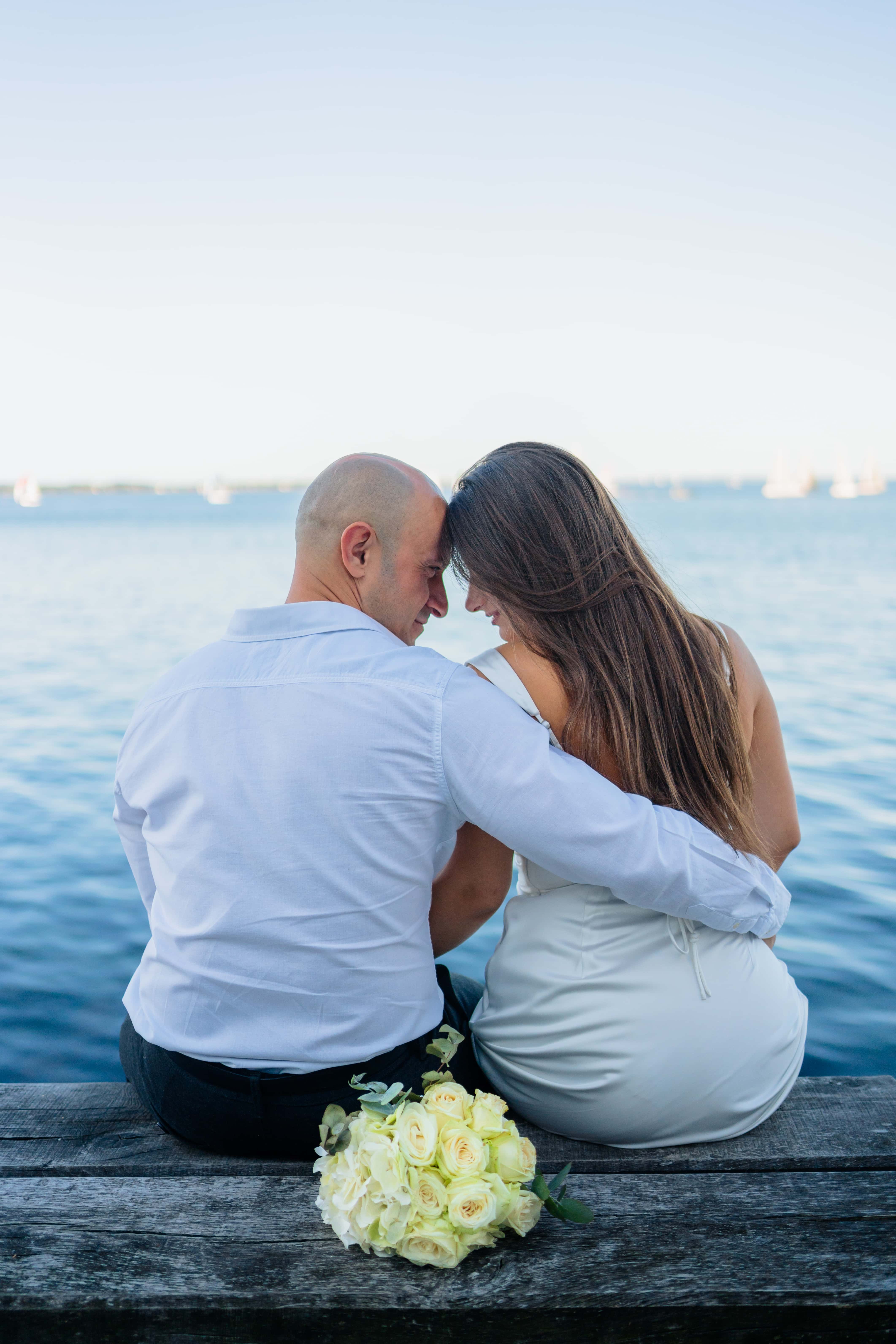 Mariés de dos sur un ponton, bouquet posé, mer et voiliers, Félix Orain photographe Bretagne